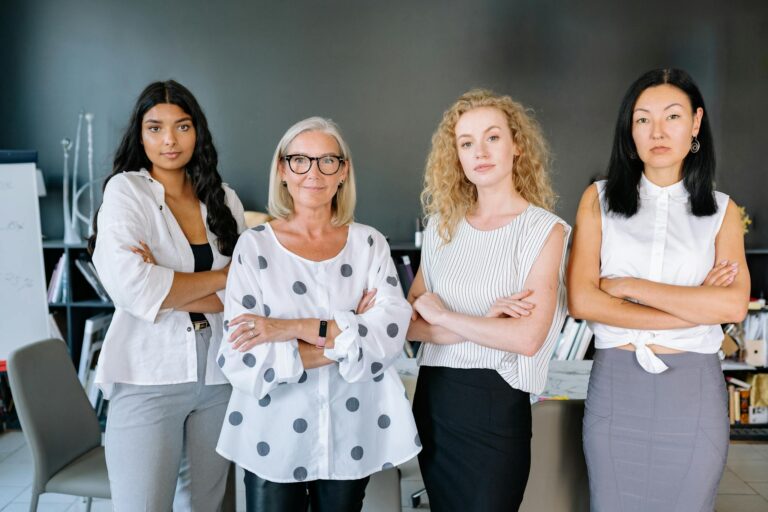 A group of confident businesswomen of diverse backgrounds standing in an office setting.